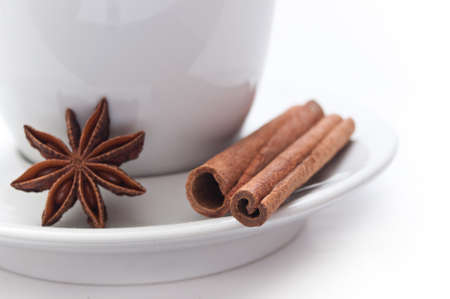 Cup of coffee with dried anise and cinnamon on white background
