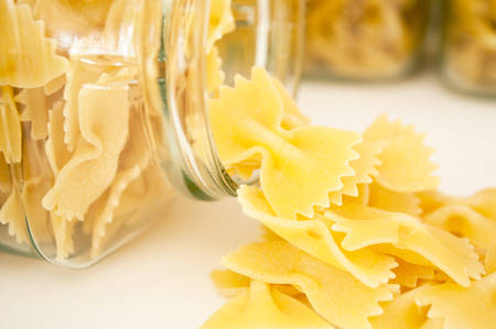 closeup of pasta falling from glass container on white backgroundの写真素材