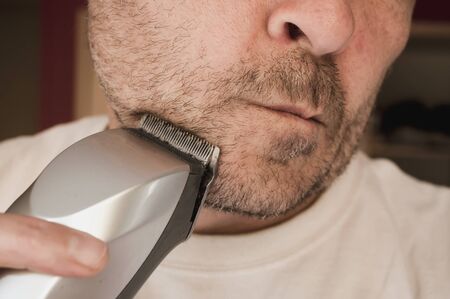 closeup of man using a mower for his beardの写真素材