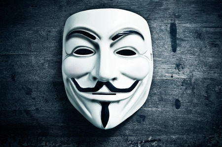 Paris - France - 8 November 2015 - Vendetta mask on wooden background . This mask is a well-known symbol for the online hacktivist group Anonymousのeditorial素材