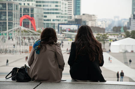 women sitting on stairs in La defense arch in Parisの写真素材