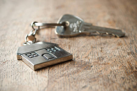 metallic key with house shaped key chain on wooden backgroundの写真素材
