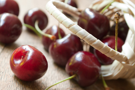 closeup of cherries in a wooden basket on wooden table backgroundの写真素材