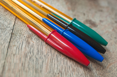 closeup of various colors of pen on wooden desk background