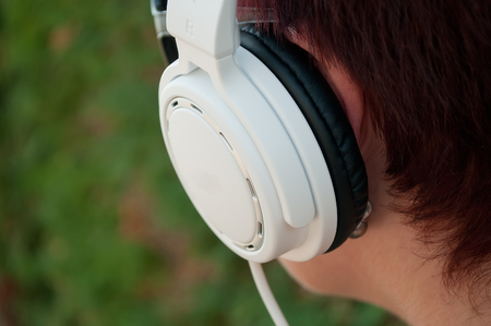 closeup of woman with white headphones in outdoorの写真素材