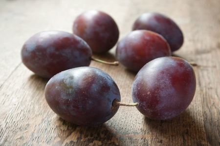 closeup of purple plums  on wooden table backgroundの写真素材
