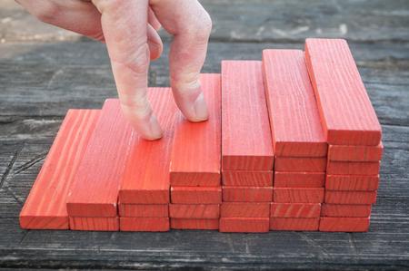  closeup of red wooden stair with  piece of wooden brick of construction game on wooden backgroundの写真素材