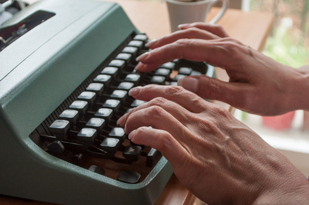 closeup of  hand of woman with typewriter  and cup of coffee の写真素材