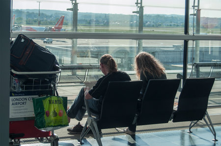 BASEL - Switzerland - 5 MAY 2017 - couple of tourists waiting in boarding hall  with a suitcase  at the airportのeditorial素材