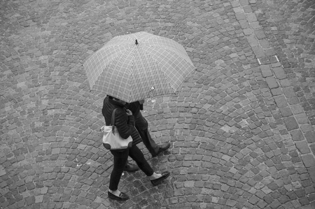 portrait of couple  with umbrella on cobbles place in the cityの写真素材