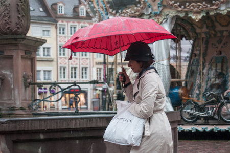 MULHOUSE - France - 6 May 2017 - portrait of woman with red umbrella on cobbles main place in the cityのeditorial素材