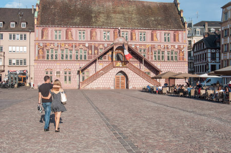 MULHOUSE - France - 2 June 2017 - couple walking on main place traditional architecture with terraces of restaurant in front of the ancient city hallのeditorial素材