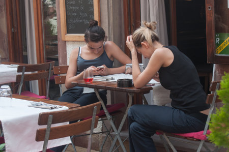 STRASBOURG - France - 1 August 2017 - two women with smart phone in restaurant terraceのeditorial素材