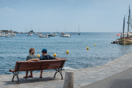 CADAQUES - Spain - 16 August 2017 - couple of lovers sitting on bench near the coastのeditorial素材