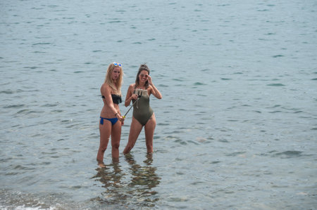 CADAQUES - Spain - 16 August 2017 - Two sexy girls in swimsuit taking a selfie in the water with smartphoneのeditorial素材