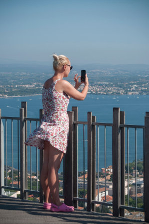 Sete - France - 18 August 2017 - Blond tourist with dress taking a picture in the windy panoramaのeditorial素材