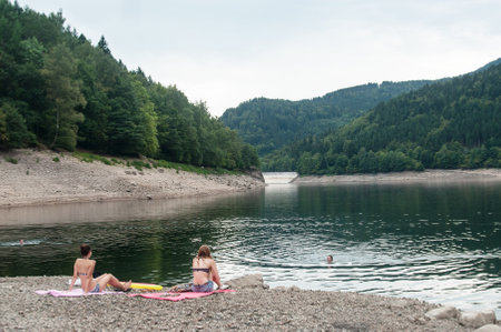 Kruth - France - 25 August 2017 - people sitting in suit swim in border lakeのeditorial素材