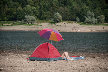 Kruth - France - 25 August 2017 - couple sitting in border lake with camping tentのeditorial素材
