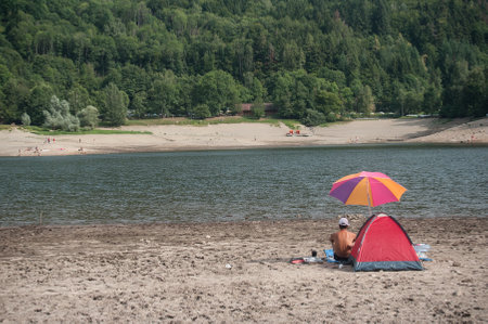 Kruth - France - 25 August 2017 - couple sitting in border lake with camping tentのeditorial素材