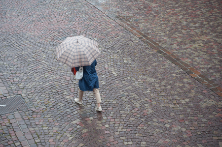 portrait of woman with umbrella on cobbles place in the cityの写真素材