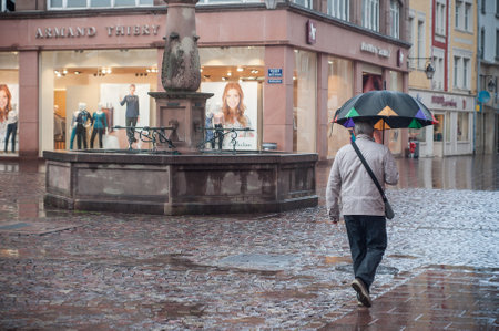 Mulhouse - France - 19 September 2017 - portrait of woman with umbrella on cobbles place with fountain in the cityのeditorial素材