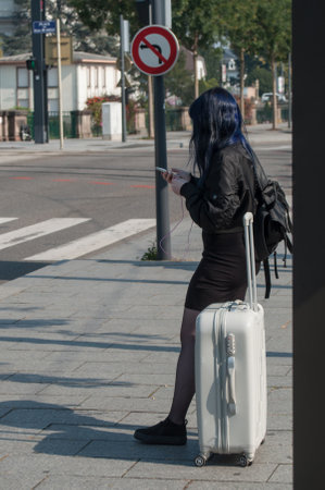 Mulhouse - France - 24 September 2017 - Woman waiting with suitcase in front of the train stationのeditorial素材