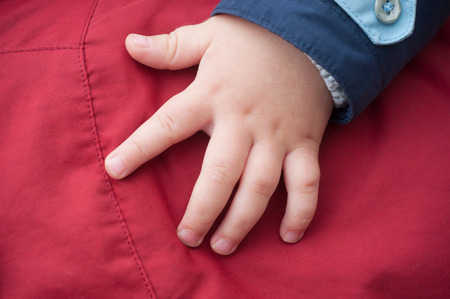 closeup of hand of baby in outdoor on red coatの写真素材