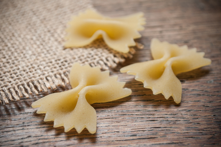 closeup of shaped butterfly pasta and hessian decoration on wooden background の写真素材