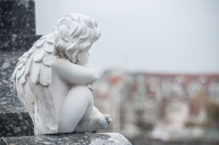 closeup of stoned angel sitting on tomb in a cemeteryの写真素材