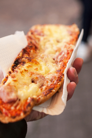 closeup of man hand with pizza in bread in the streetの写真素材