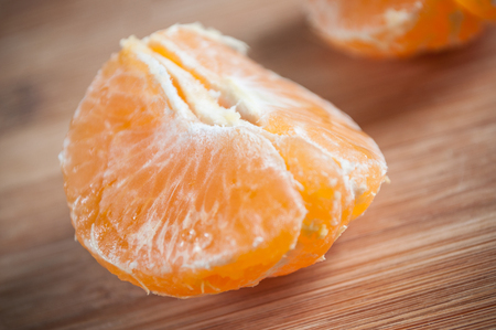 closeup of peeled tangerine on wooden cutting board backgroundの写真素材