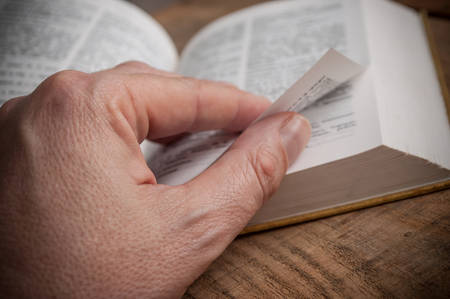 closeup of man hand on book on wooden background