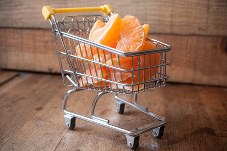 closeup of mini trolley with tangerine quarter on wooden backgroundの写真素材
