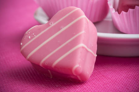 closeup of pink shaped heart pastry on pink background for valentines day