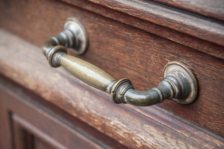 closeup of bronze handle on brown wooden door