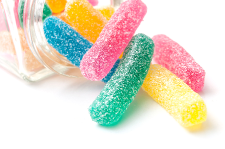 closeup of traditional acidulated candies faling from glass container on white background の写真素材