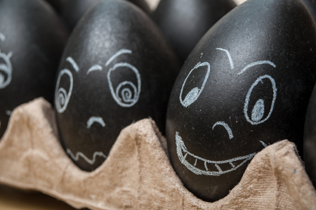 closeup of black funny easter eggs with expressive face drawn in chalkの写真素材