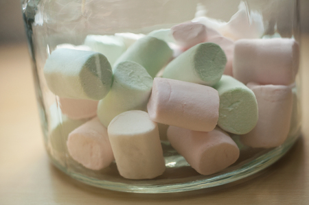 closeup of marshmallows in glass container on wooden table backgroundの写真素材