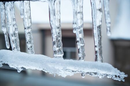 closeup of ice stalactites on window of houseの写真素材