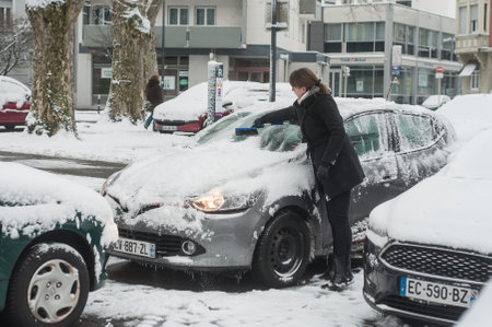 Mulhouse - France - 18 March 2018 - woman removes snow on her car on a parkingのeditorial素材