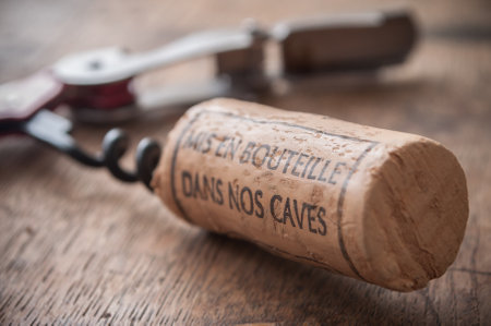 closeup of corks wine and pulls caps on wooden background with french text "mis en bouteille dans nos caves" traduction of bottled in our cellarsのeditorial素材