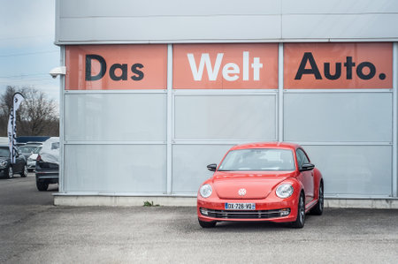 Mulhouse - France - 30 March 2018 - orange Volkswagen new beetle in front of  Volkswagen showroom - Volkswagen is a german brand of automotive and the new beetle is the new ladybugのeditorial素材