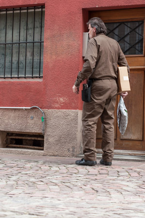Mulhouse - France - 3 April 2018 - UPS delivery worker waiting with packages  in the street in front of building entryのeditorial素材