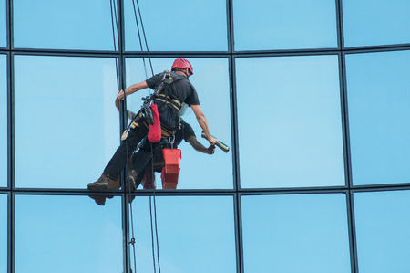 Portrait of worker washing windows of the modern building.