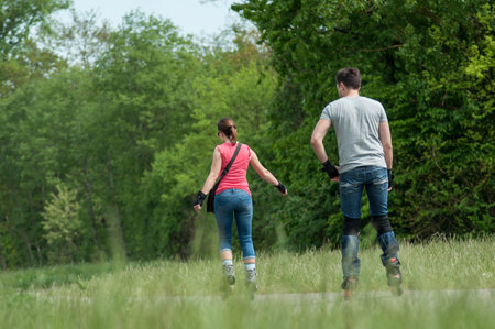 Mulhouse - France - 29 April 2018 - couple   in blue jeans drives roller skates in border forestのeditorial素材