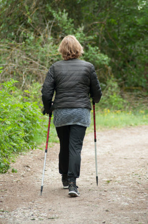 Reinningue - France -4 May 2018 -  woman with sticks walking in the way in nature landscapeのeditorial素材