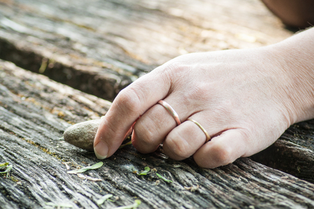 closeup of hand of womanwith pebble    for balance on wooden tableの写真素材