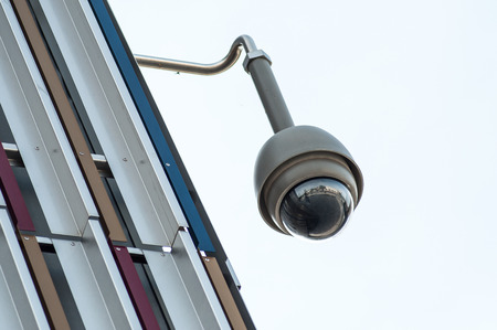 closeup of security camera on modern building  on grey sky background