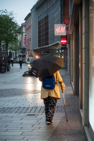 Mulhouse - France - 16 May 2018 - woman walking in the street with umbrella in the morning by rainy dayのeditorial素材