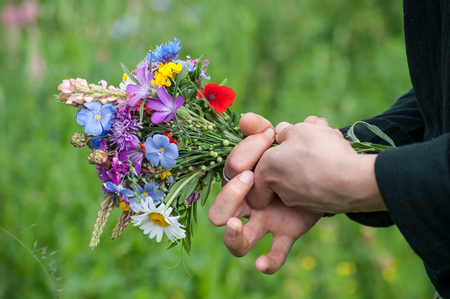 closeup of wild flowers bouquet in hand of young woman in a meadowの写真素材